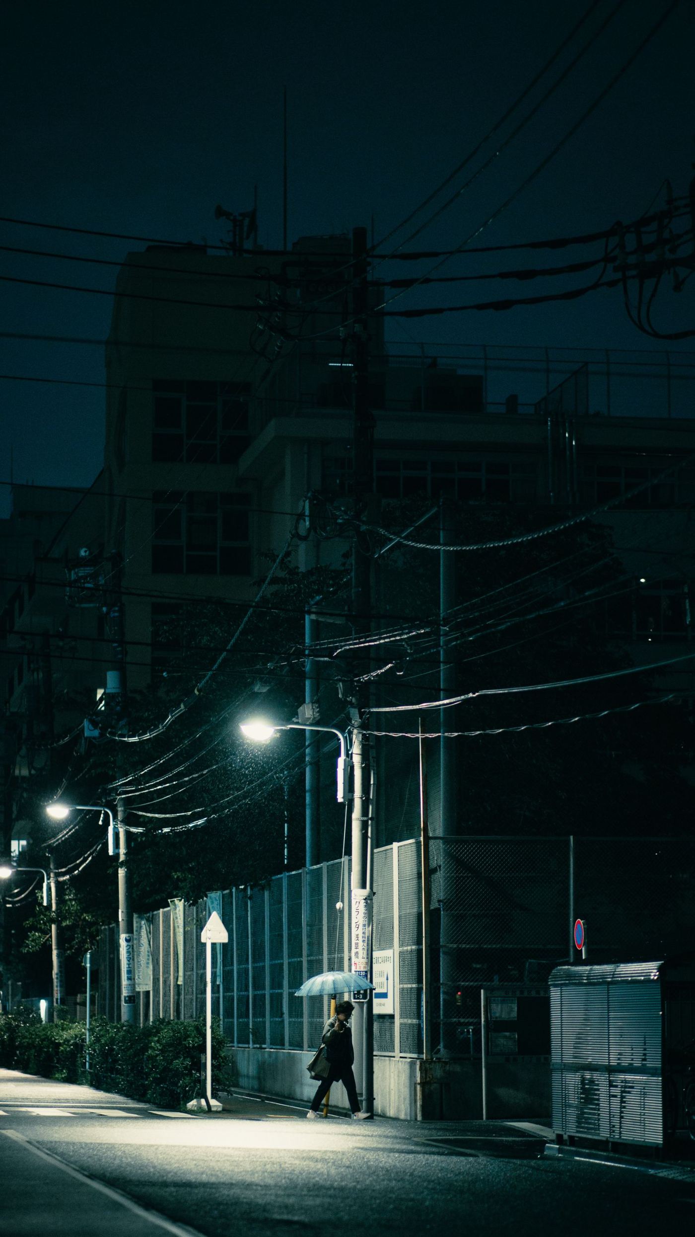A person with an umbrella on a rainy street at night, by Nate Tran
